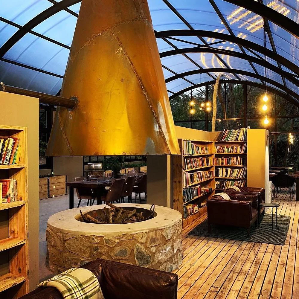 A library with an open fire under a glass roof